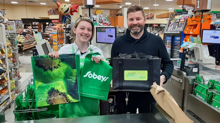 New Hamburg Sobeys Front End Clerk Ashley Cutting and franchise owner Bill Fleming with some of the options available to customers who come without their own shopping bags